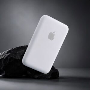 White MagSafe-compatible power bank on black rock with gray background.