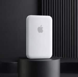 White MagSafe-compatible power bank with Apple logo on a black stand.