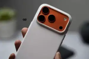 White silicone protective case with orange camera cutout for iPhone 17 Pro Max.